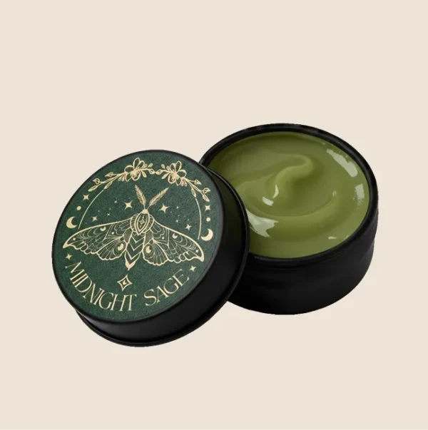 A tin of green comfrey salve with the midnight sage logo on the lid.