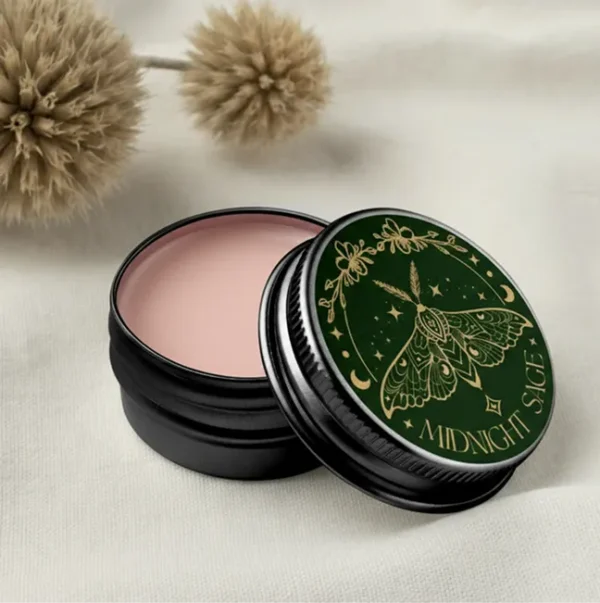 A tin of rose salve resting on a cotton sheet, with tree seeds behind it.